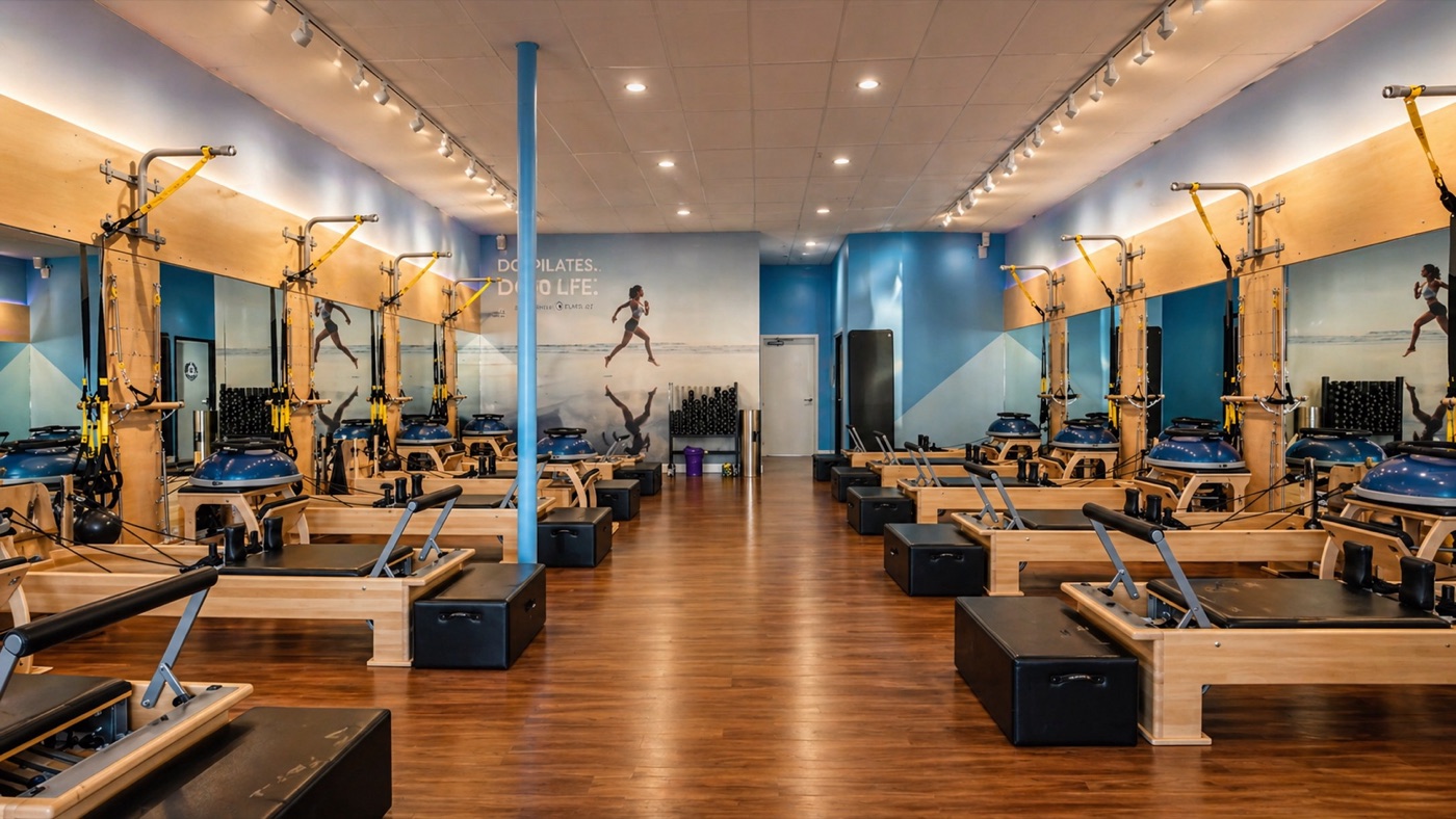 Club Pilates franchise studio with rows of reformers lit by track lighting and warm LED wall accents