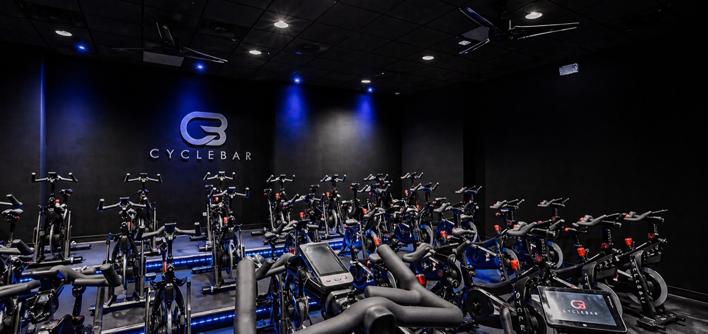 CycleBar franchise indoor cycling studio with blue accent lighting and spotlights over rows of bikes