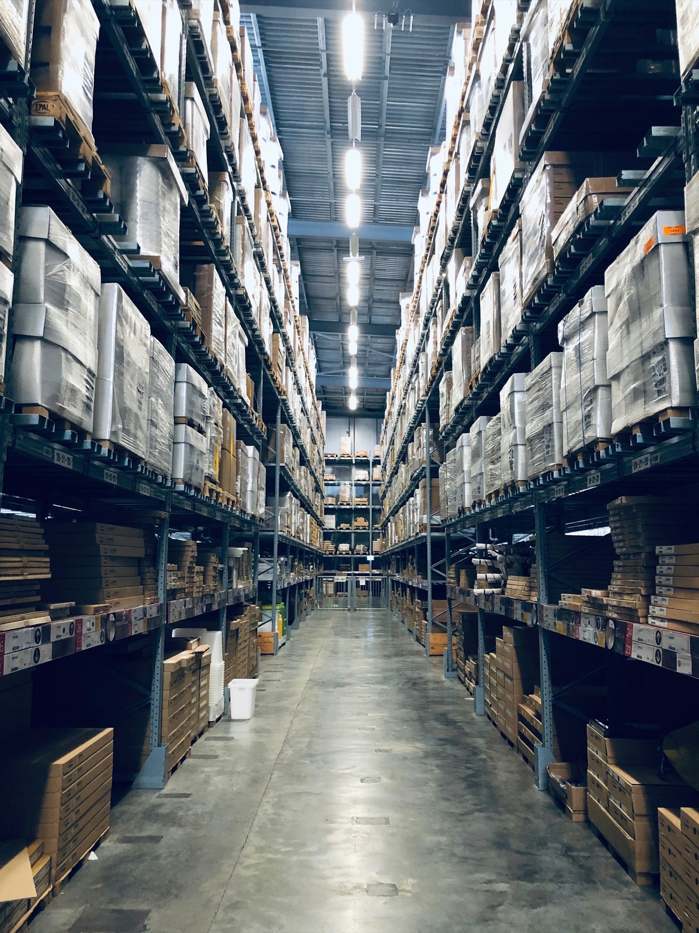 Distribution warehouse aisles with tall racks of boxed product for franchise lighting rollouts